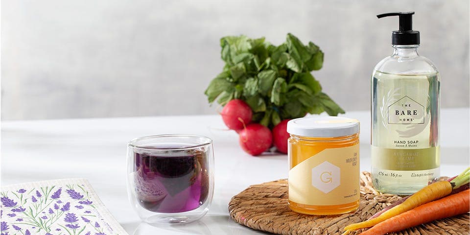 housewarming gift with honey, liquid soap, purple tea, a dishcloth and radishes in the background