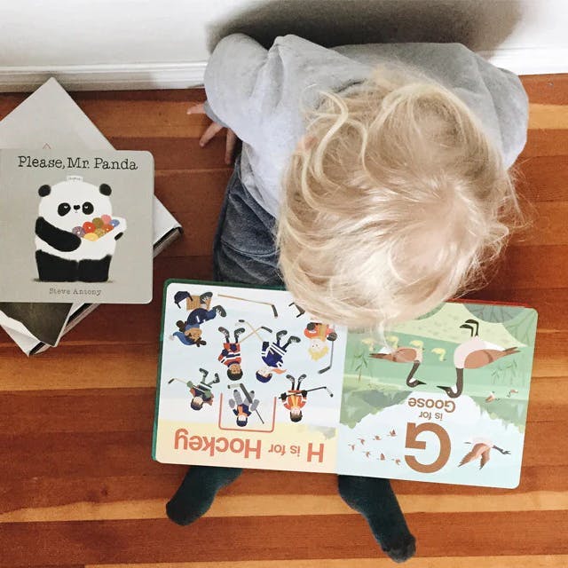 baby with blonde haird reading baby books