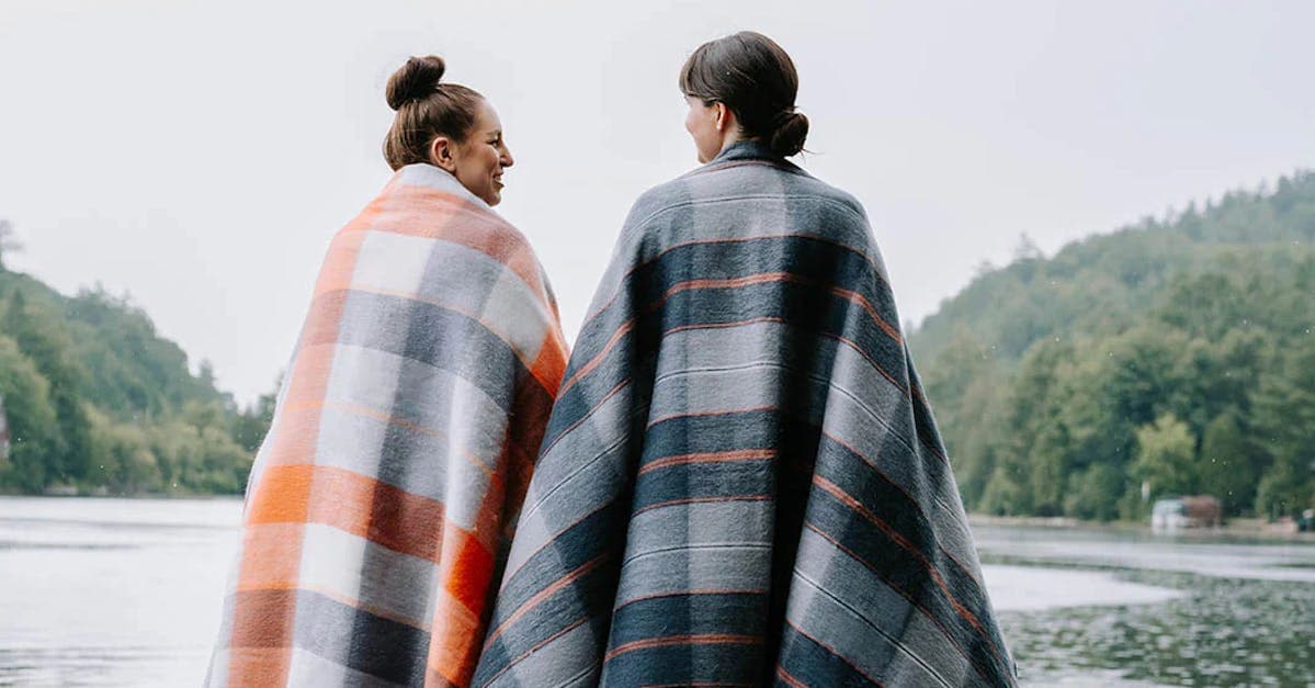 two women looking out at the lake, wrapped in plaid pokoloko blankets